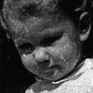 Young child holding adult's hand outdoors.