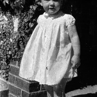 Young girl in vintage dress posing outdoors.