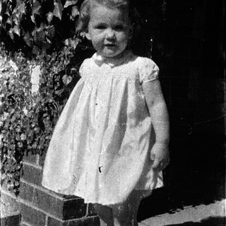 Young girl in vintage dress posing outdoors.