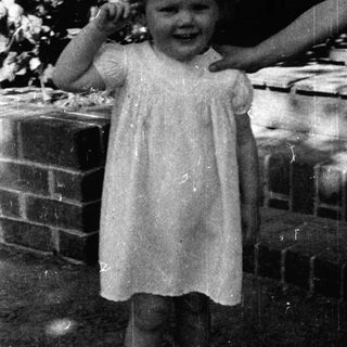 Young girl in vintage dress smiling outdoors.