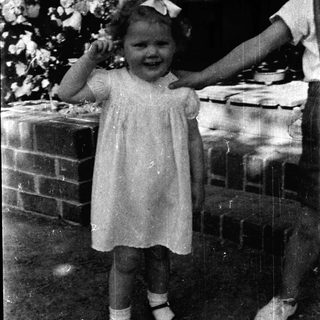 Young girl in vintage dress smiling outdoors.
