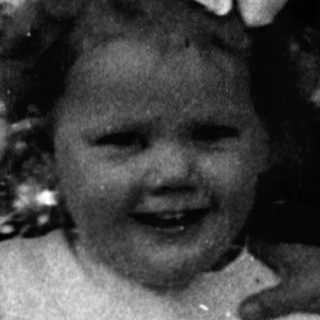 Young girl in vintage dress smiling outdoors.