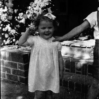 Young girl in vintage dress smiling outdoors.