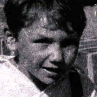 Young boy sitting on brick steps smiling.