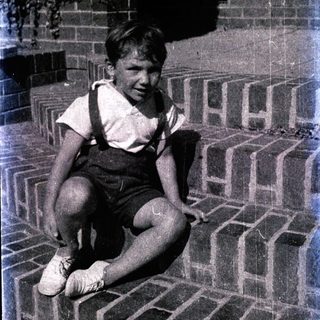 Young boy sitting on brick steps smiling.