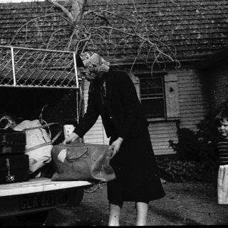 Two people loading luggage into a truck.