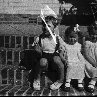 Four children sitting on steps holding kites.