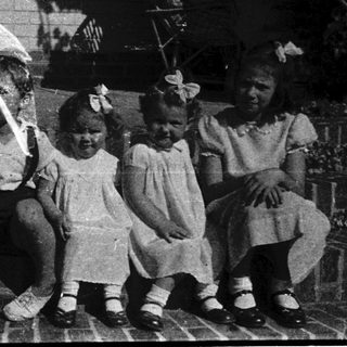 Four children sitting on steps holding kites.