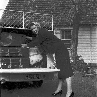 Woman loading suitcases into vintage truck.