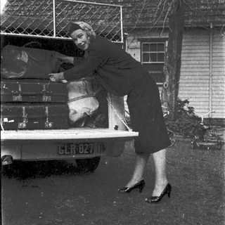Woman loading suitcases into vintage truck.