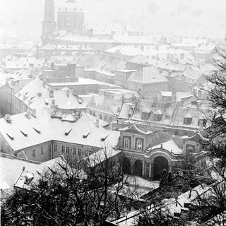 Snow-covered historic European cityscape with winter fog.