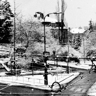 Tram tracks converging at urban intersection with snow.