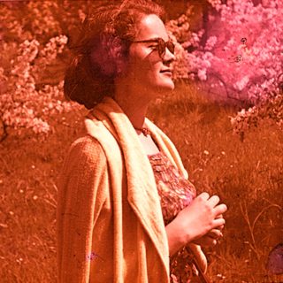 Woman in vintage clothing standing outdoors in sunlight.