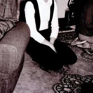 Woman sitting on floor in vintage-style living room.