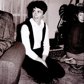Woman sitting on floor in vintage-style living room.