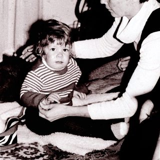 Family members interacting indoors, focusing on a young child.