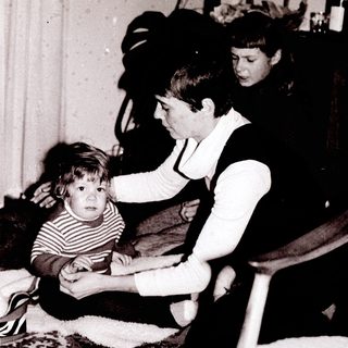 Family members interacting indoors, focusing on a young child.