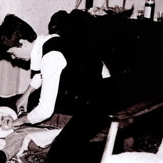 Woman dressing a baby indoors.