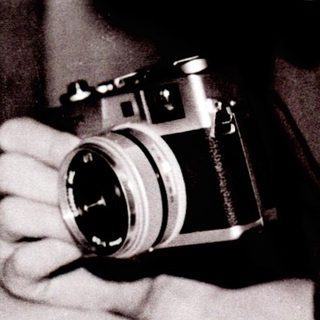 Person examining old photographs with vintage camera.