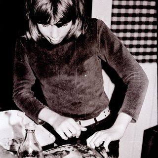 Person basting roasted meat on a tray.