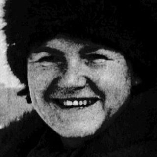 Smiling woman in winter coat and fur hat outdoors.