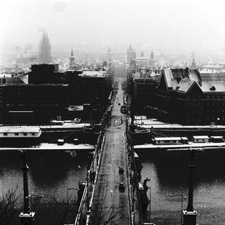 Snowy city street along canal, foggy winter scene.