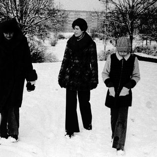 Three people walking in snow-covered outdoor setting.