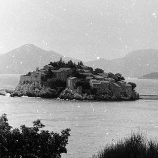 Isolated fortress on rocky island in calm waters.