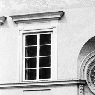 Historic building exterior with clock and pedestrians.