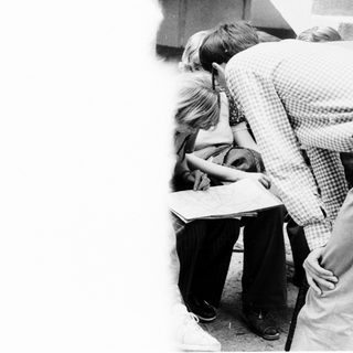 Two people working closely on a desk.