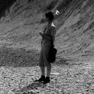 People walking along a coastal gravel path.