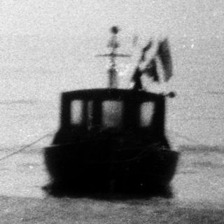 Small boats on calm sea near shore.