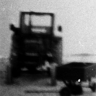 Miniature scene of beach with toy boat, cart, and box.