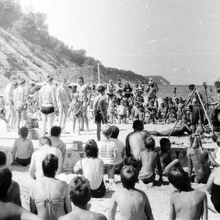 Group of people watching beachside performance or ceremony.