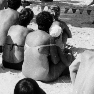 Shaved men performing ritual on beach.
