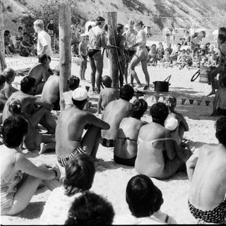 Shaved men performing ritual on beach.