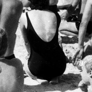 Beach scene with crowd watching military parade.