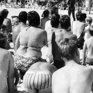 Beach scene with crowd watching military parade.