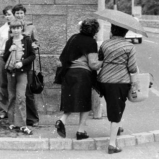 People waiting at a monument plaque on rainy day.