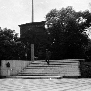 Memorial monument with star emblem, person ascending stairs.