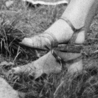 Woman knitting outdoors on a chair.