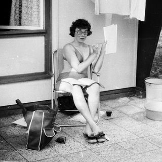 Woman sitting outside writing by door.