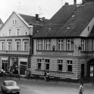 Historic European street scene with old buildings and vintage cars.