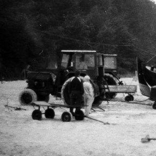 Fishing boat and tractor on sandy shore.