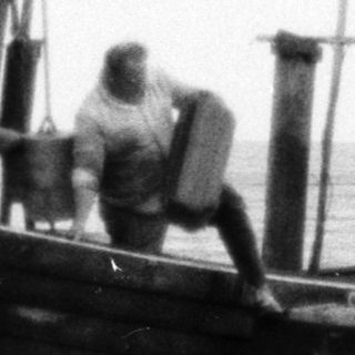 Old fishing boat on shore with three people.