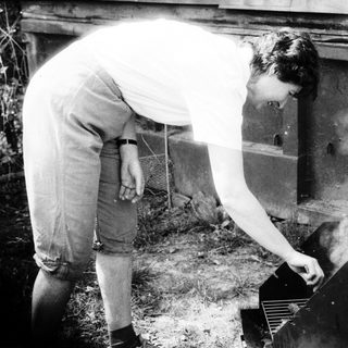 Person tending outdoor stove with smoke.