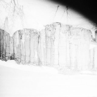 Snow-covered stone wall in winter landscape.