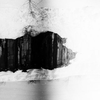 Snow-covered cliff with exposed dark rock layers.