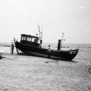 Beached fishing boat with tractor and equipment.