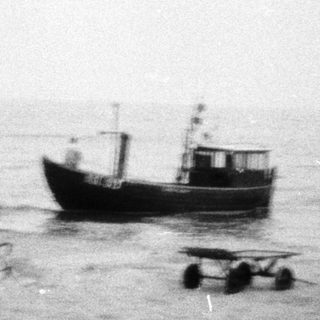 Beached boat and construction vehicles on shore.